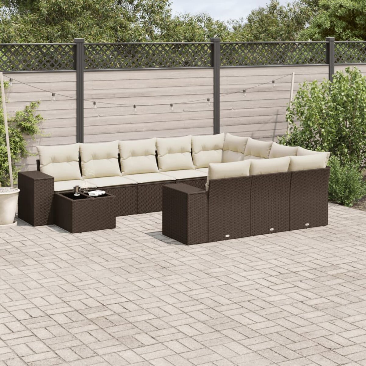 Dunkelbraunes Korbmöbel mit beigen Kissen und einem quadratischen Tisch auf der Terrasse.