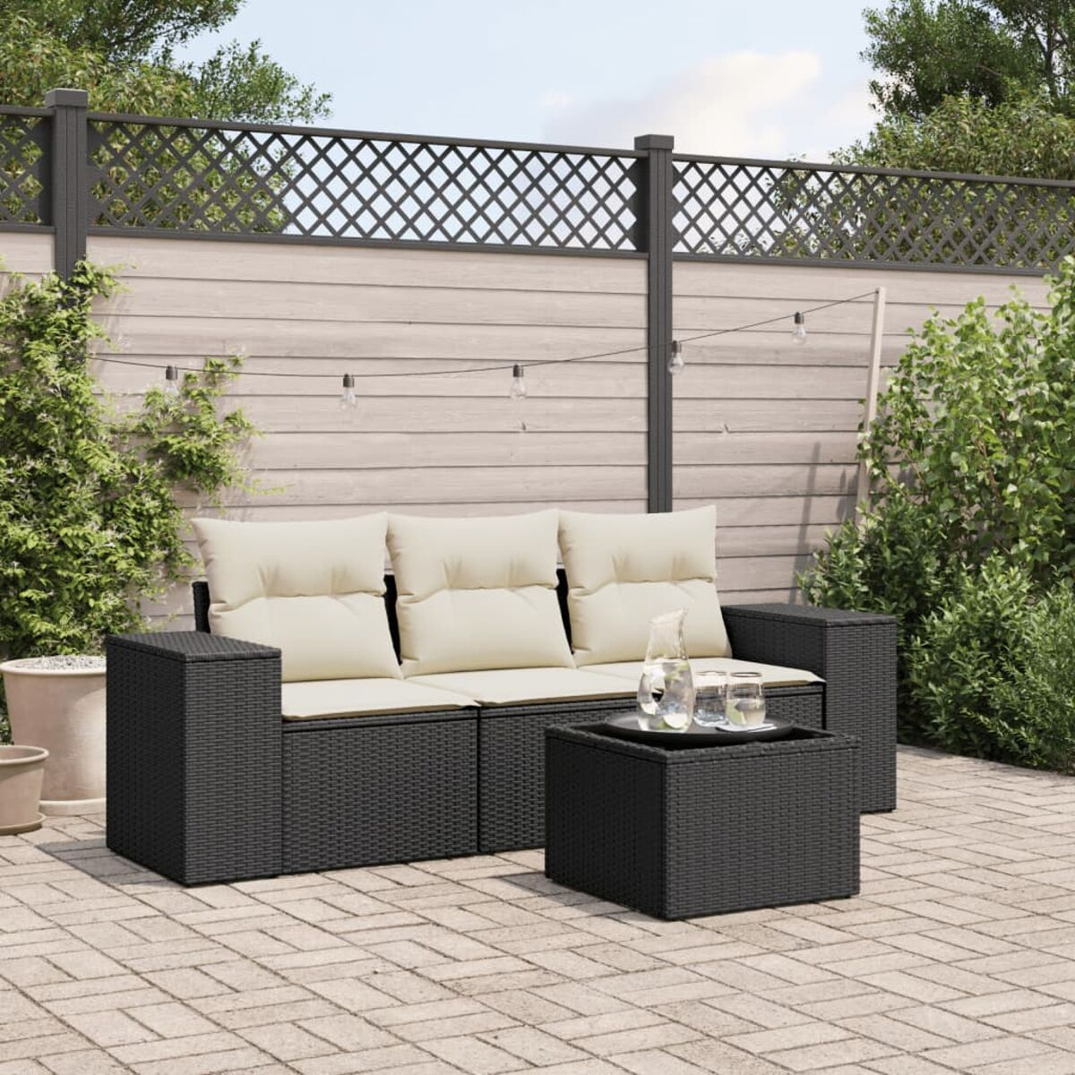 Schwarzes Ecksofa aus Korbgeflecht mit beigen Kissen und einem Tisch auf einer Terrasse.