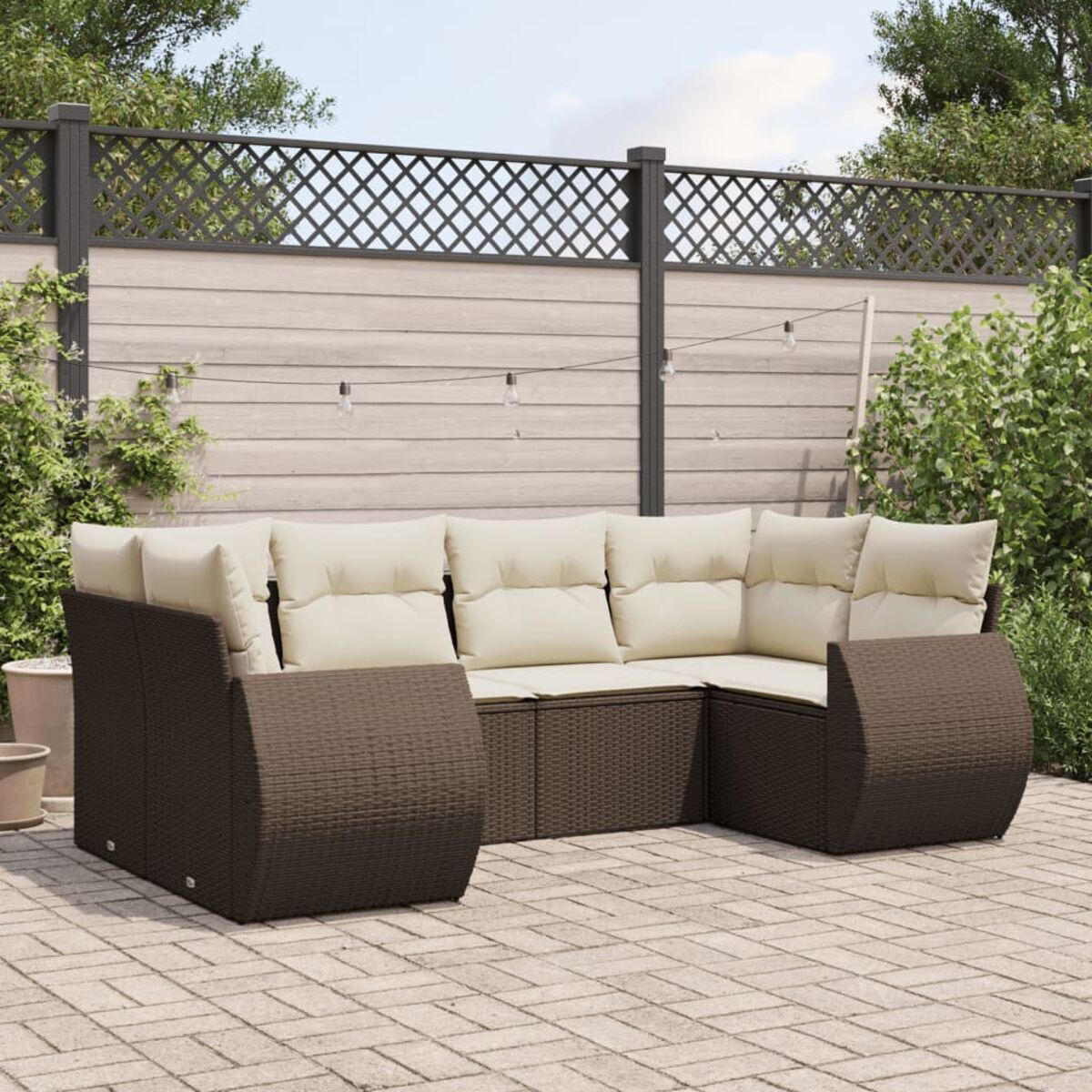 Set divani esterni in rattan marrone con cuscini beige su un patio in mattoni con sfondo giardino.