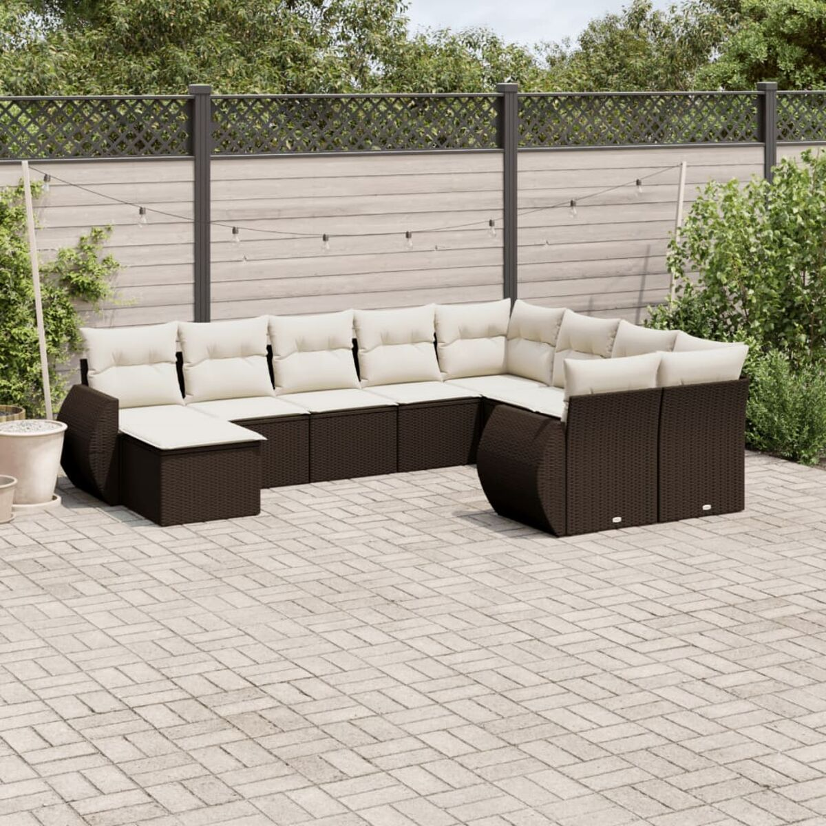 Set da patio all'aperto con mobili in rattan marrone. Include divano, sedie e un tavolino. Sono presenti cuscini neri.