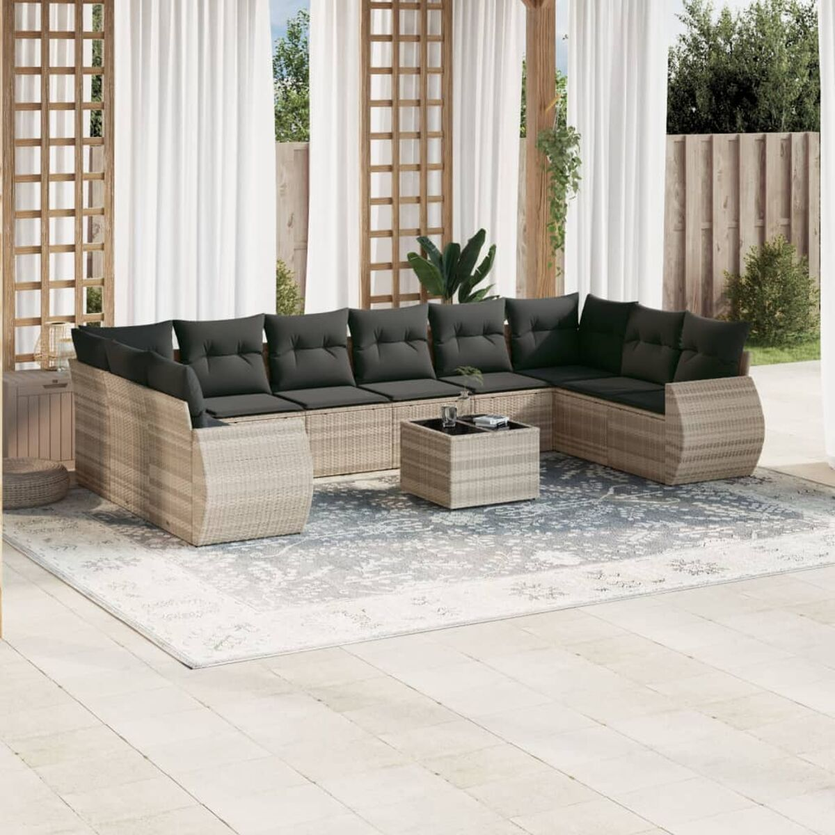 Rattansofa-Set mit dunklen Kissen auf einem Teppich, Outdoor-Setting.