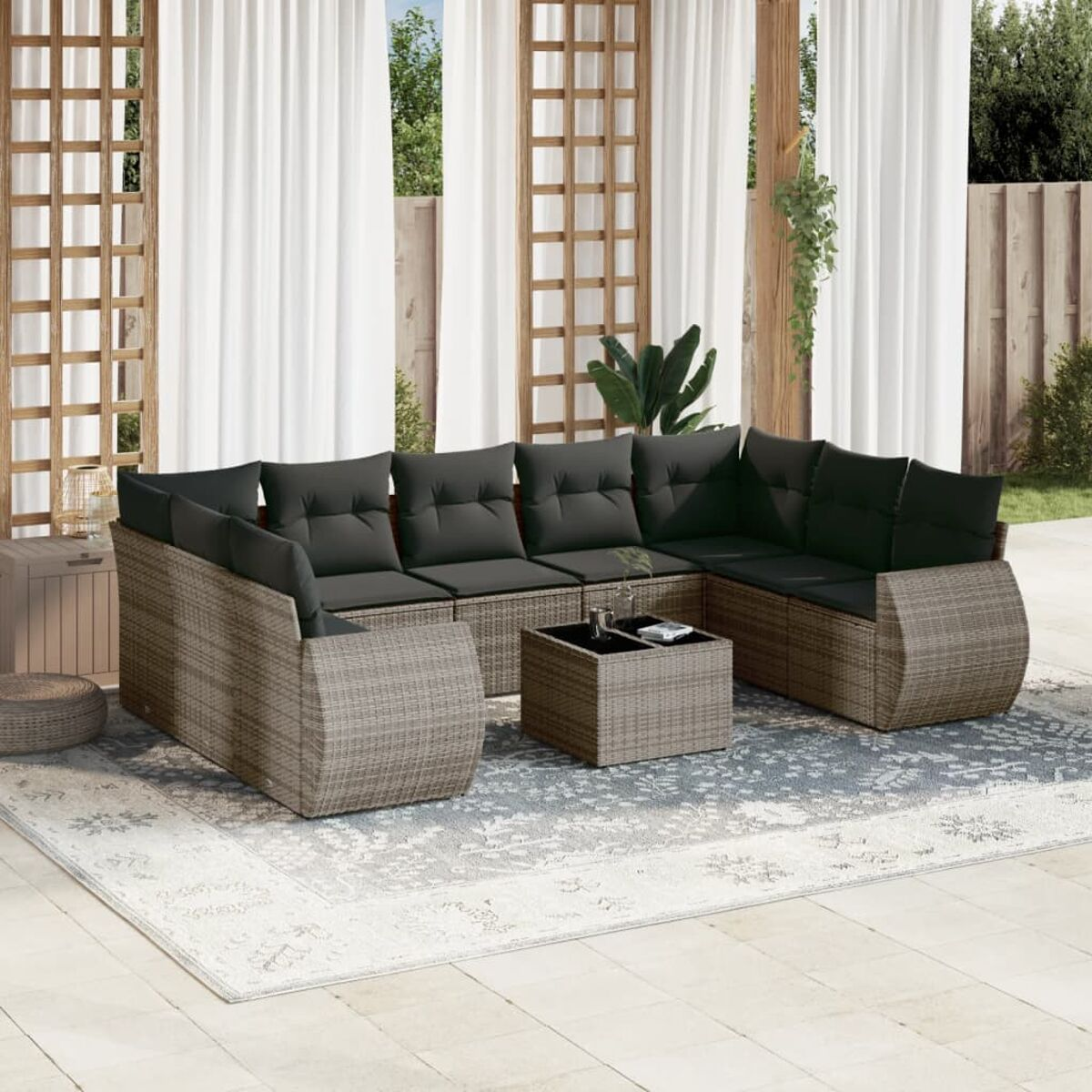 Outdoor-Ecksofa mit dunklen Kissen und Couchtisch auf einem Teppich. Weiße Vorhänge und Holzgitter im Hintergrund.