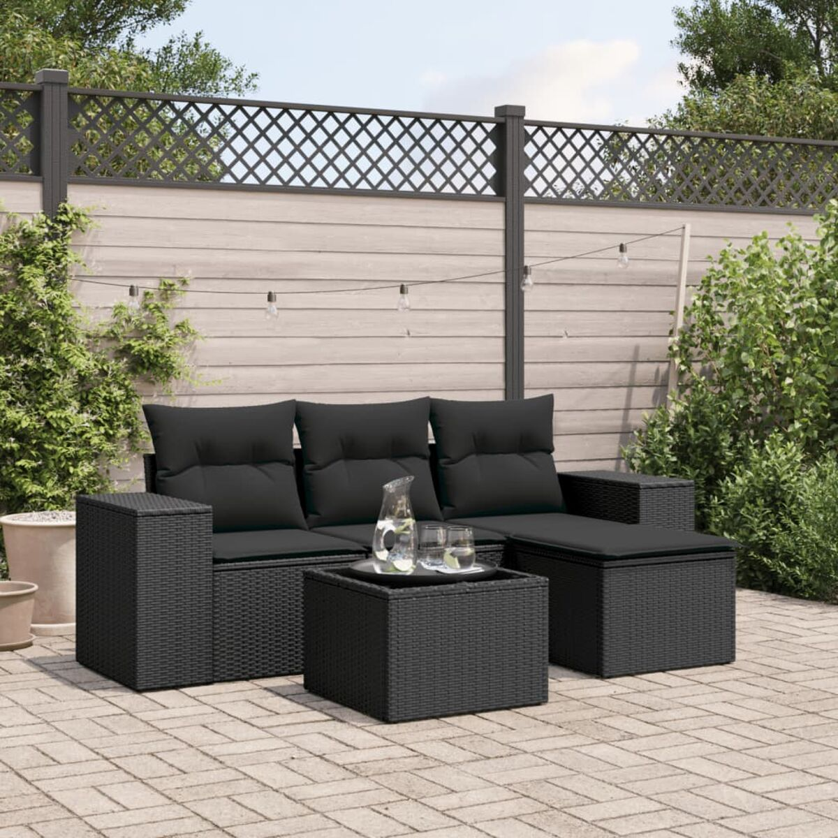 Schwarzes Rattan-Sofaset mit schwarzen Kissen, Couchtisch und Ziegel-Patio.