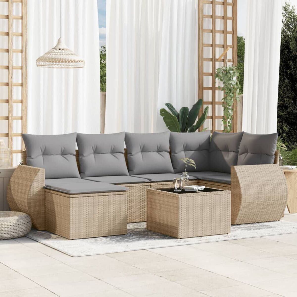 Terrassenset für den Außenbereich. Beige Ecksofa aus Korbgeflecht mit grauen Kissen. Ein kleiner Tisch und ein Teppich.