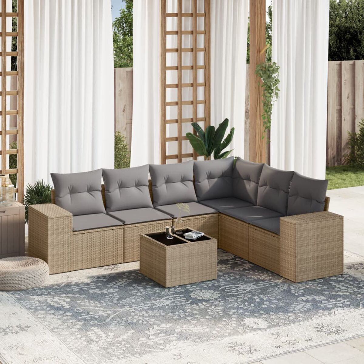 Outdoor-Terrassenset mit Rattan-Sofas, Kissen und Couchtisch. Teppich und Vorhänge schaffen eine gemütliche Atmosphäre.