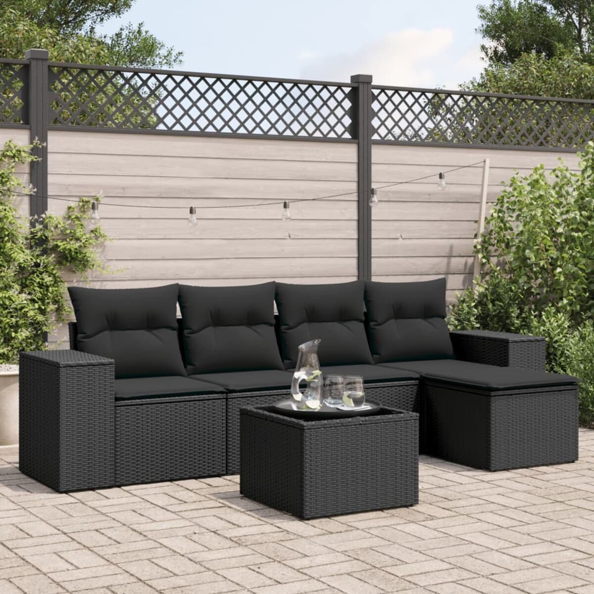 Schwarzes Outdoor-Ecksofa-Set aus Rattan mit Tisch und Pflanzen.