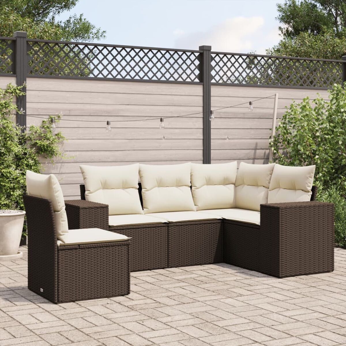 Divano componibile in vimini marrone con cuscini color crema e una sedia, su un patio.