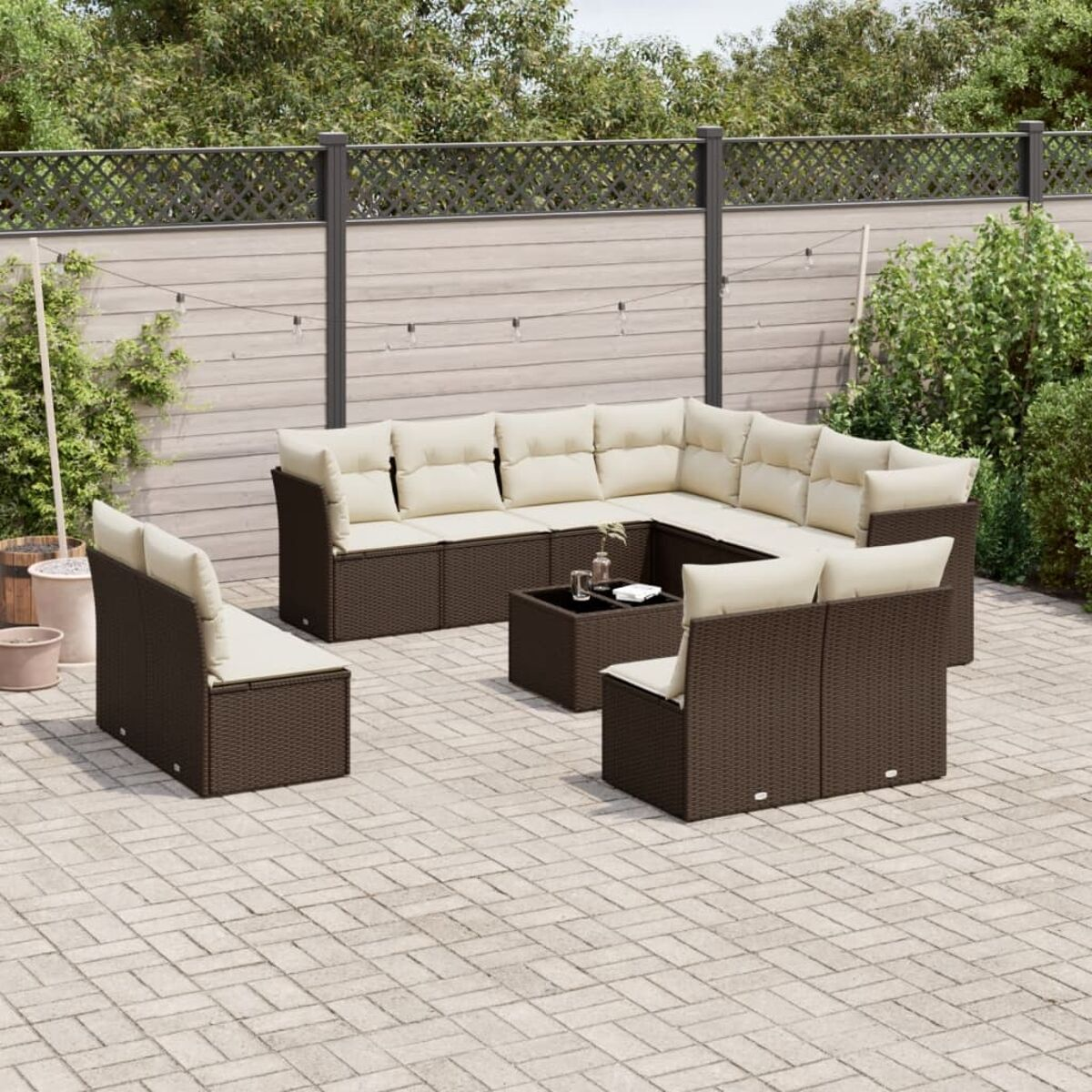 Divano angolare in vimini marrone scuro con cuscini beige e set tavolo quadrato.