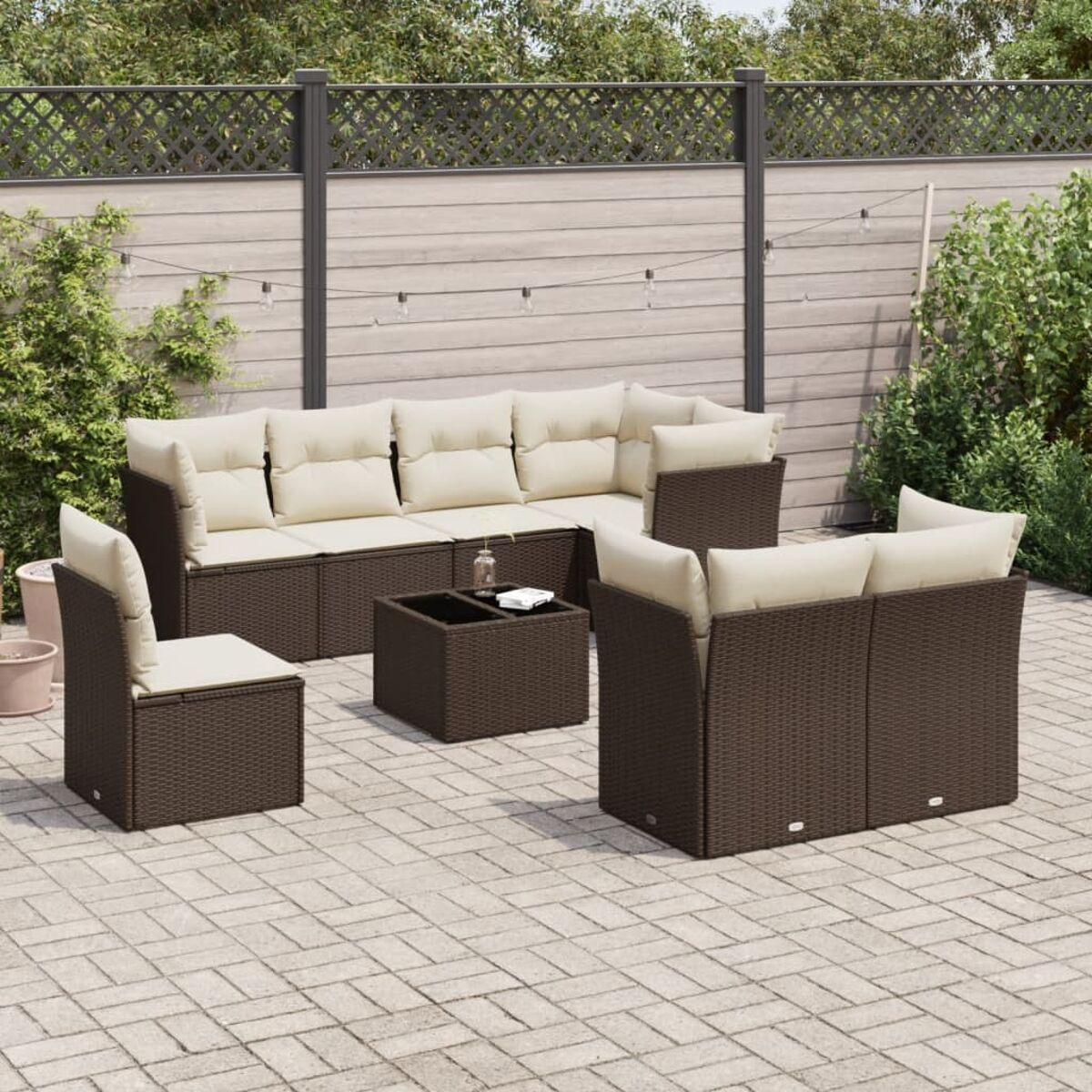 Set di mobili da esterno in vimini marrone con cuscini color crema e un tavolo, su un patio in mattoni.