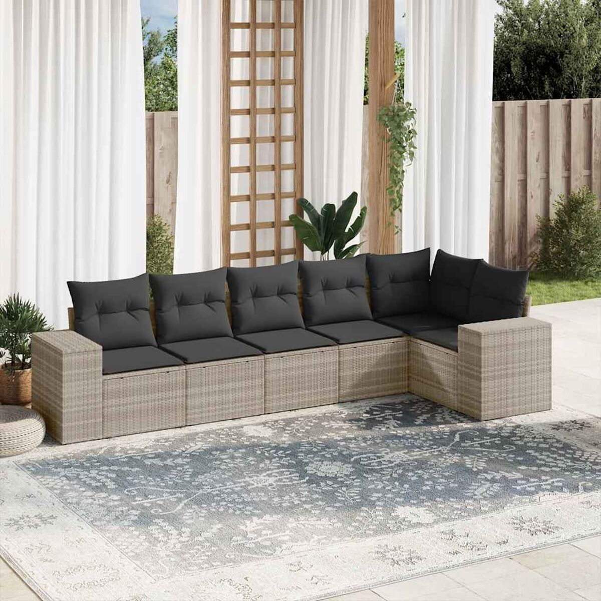 Beiges Rattan-Ecksofa mit grauen Kissen in einer Terrasseneinstellung.