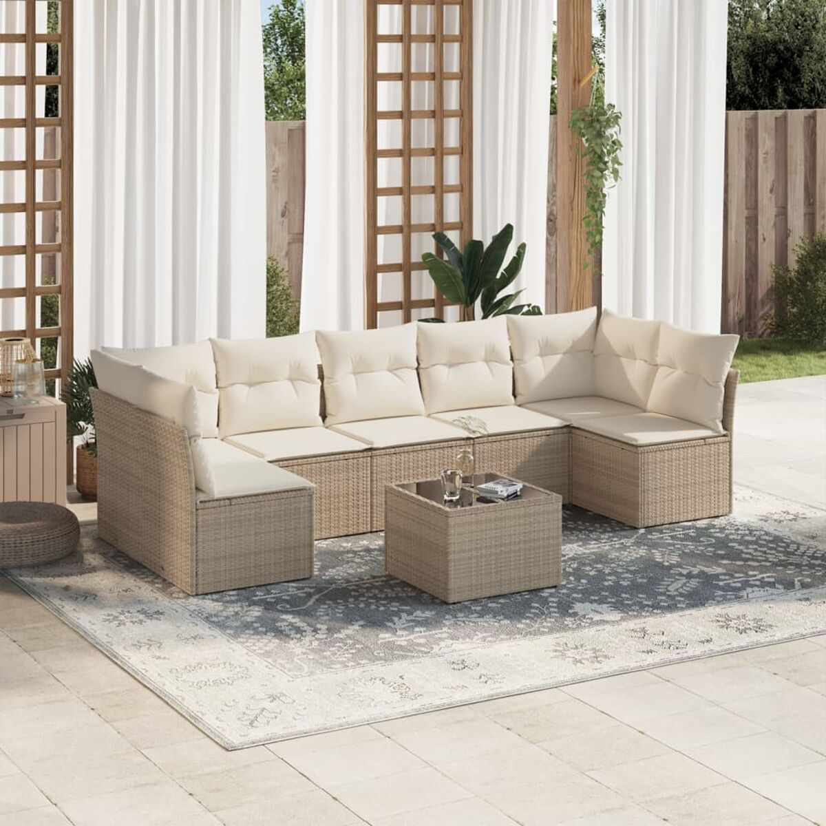 Beiges Outdoor-Ecksofa mit cremefarbenen Kissen, Couchtisch auf einem Teppich. Weiße Vorhänge im Hintergrund.