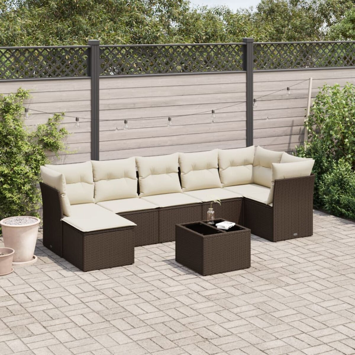 Set divani in vimini marrone con cuscini beige su un patio. Tavolo al centro.