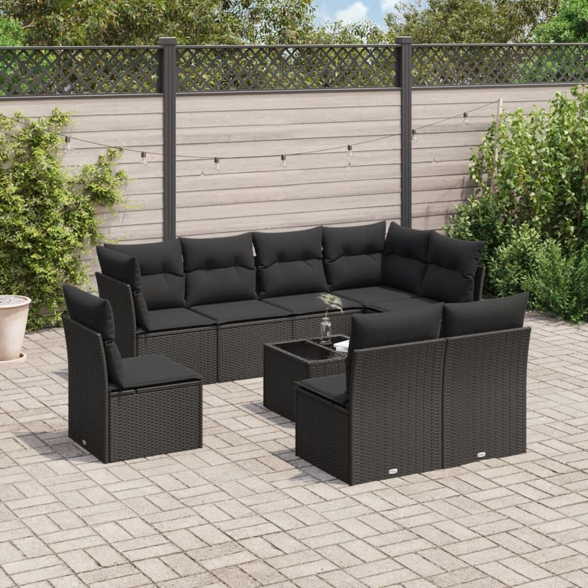 Schwarzes Outdoor-Sitzset aus Korbgeflecht mit schwarzen Kissen und einem Tisch mit Glasplatte.