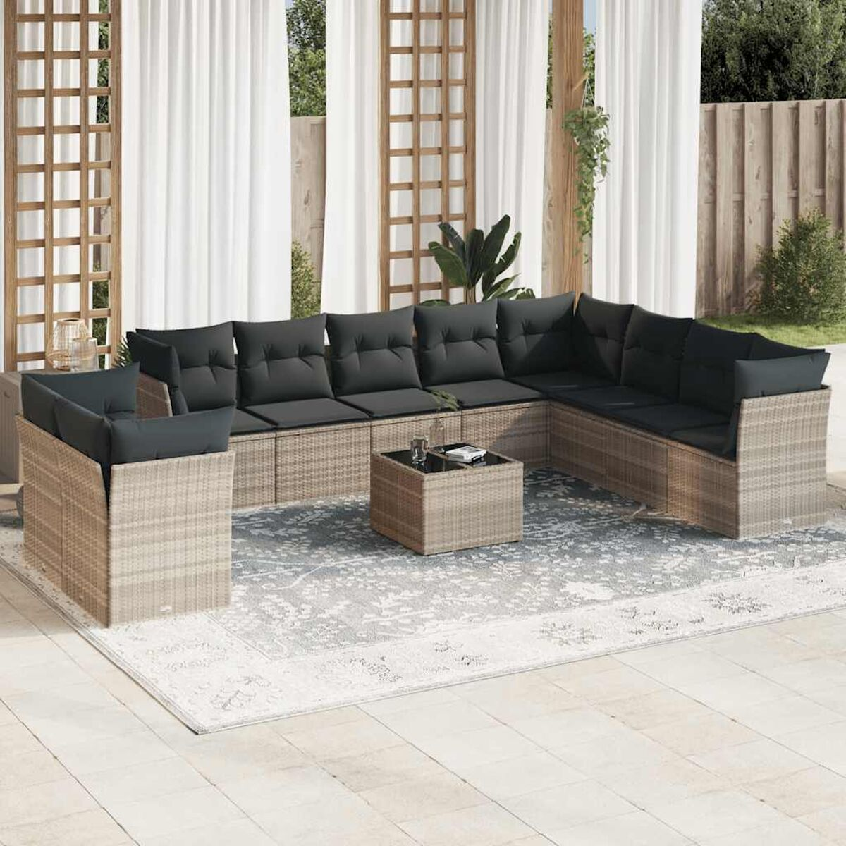 Ecksofa im Freien mit schwarzen Kissen, einem Couchtisch und einem Teppich auf einer Terrasse.