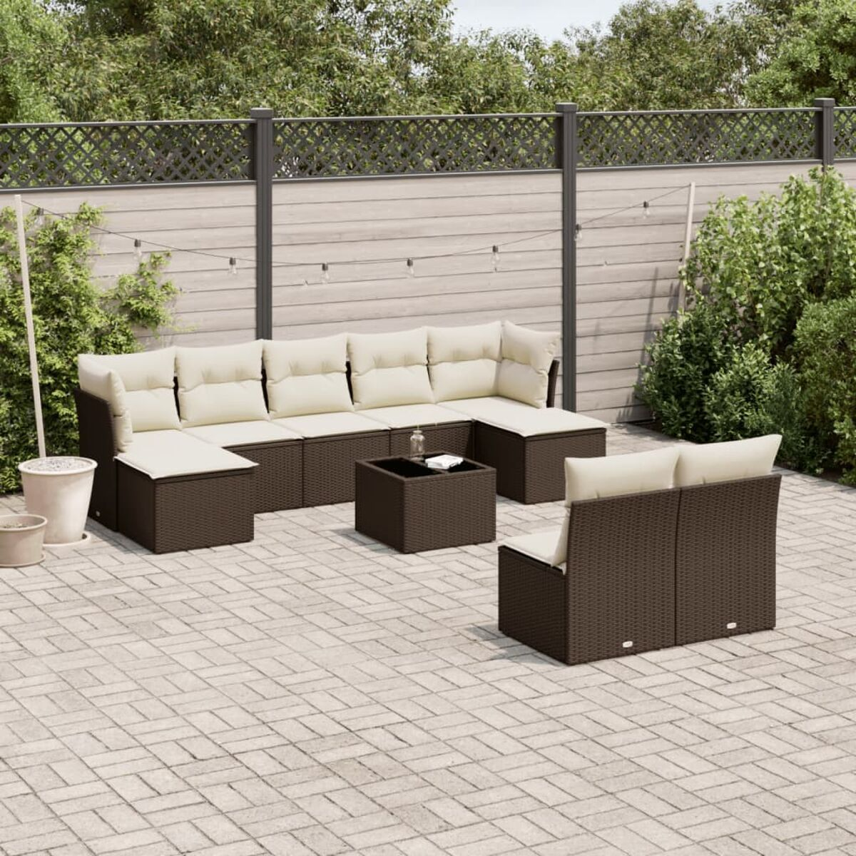 Set da esterno in rattan marrone. Cuscini beige, divano, tavolo e sedia. Patio in pietra.