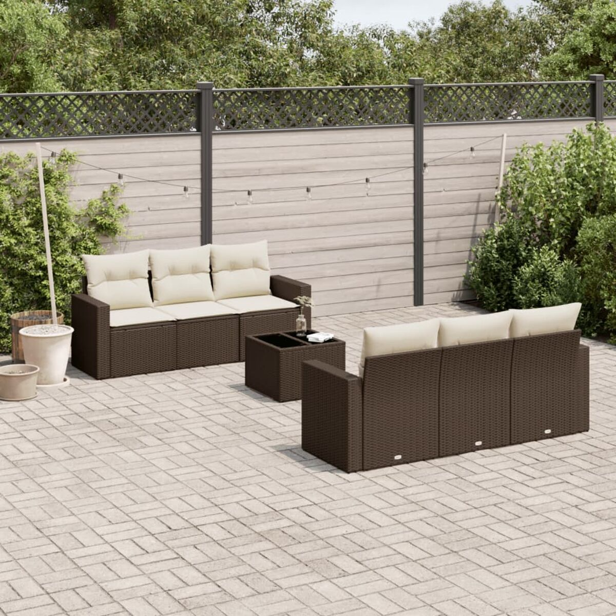 Divano componibile da esterno in vimini marrone con cuscini beige e tavolino su un patio.