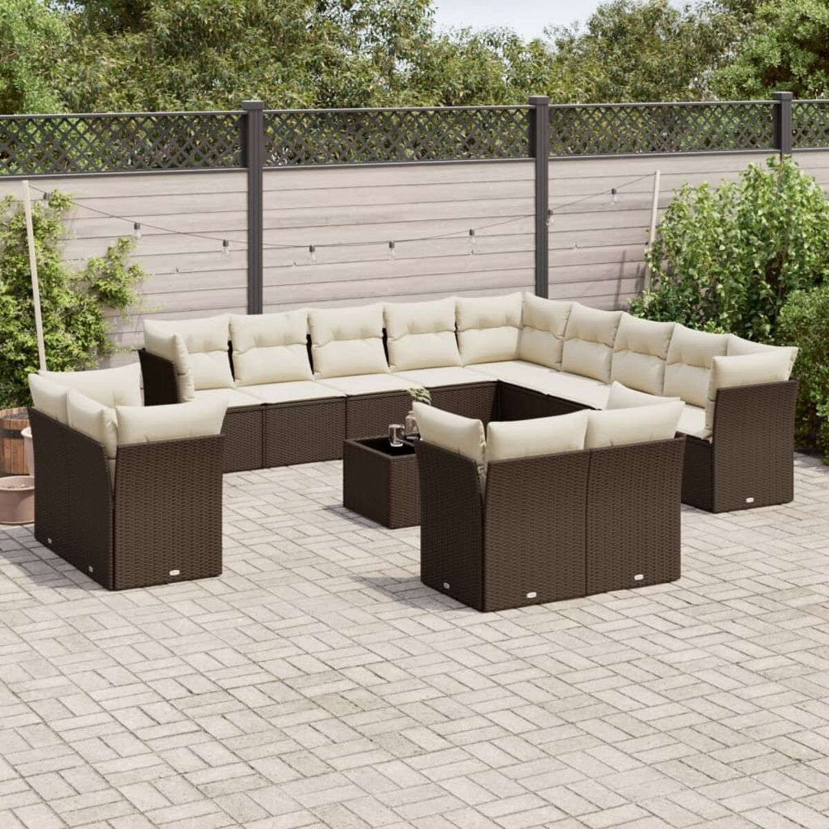 Divano componibile in vimini marrone con cuscini beige su patio in mattoni, con tavolino.