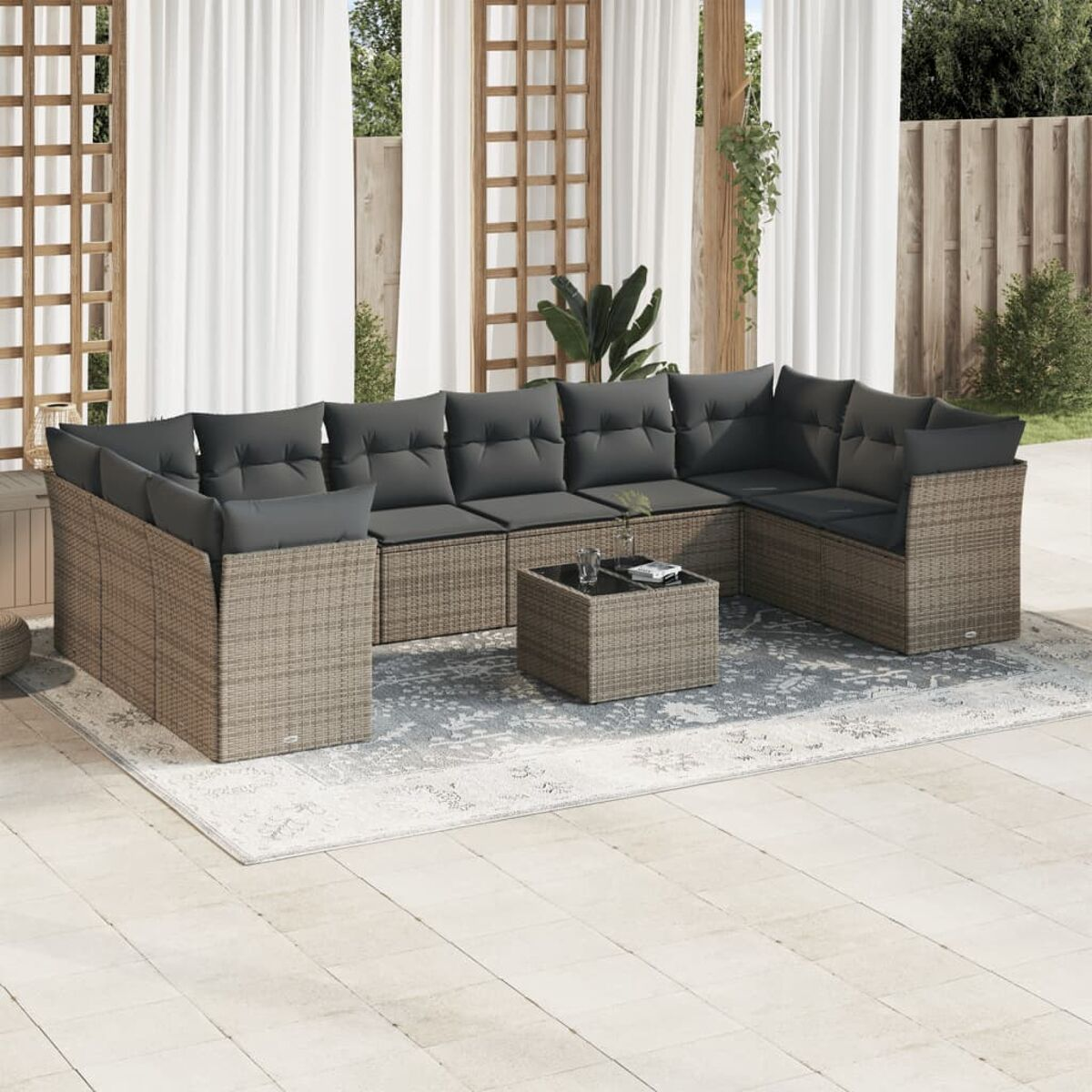Outdoor-Sitzgruppe. Graues Sofa aus Weide mit grauen Kissen. Teppich auf Terrasse, kleiner Tisch.