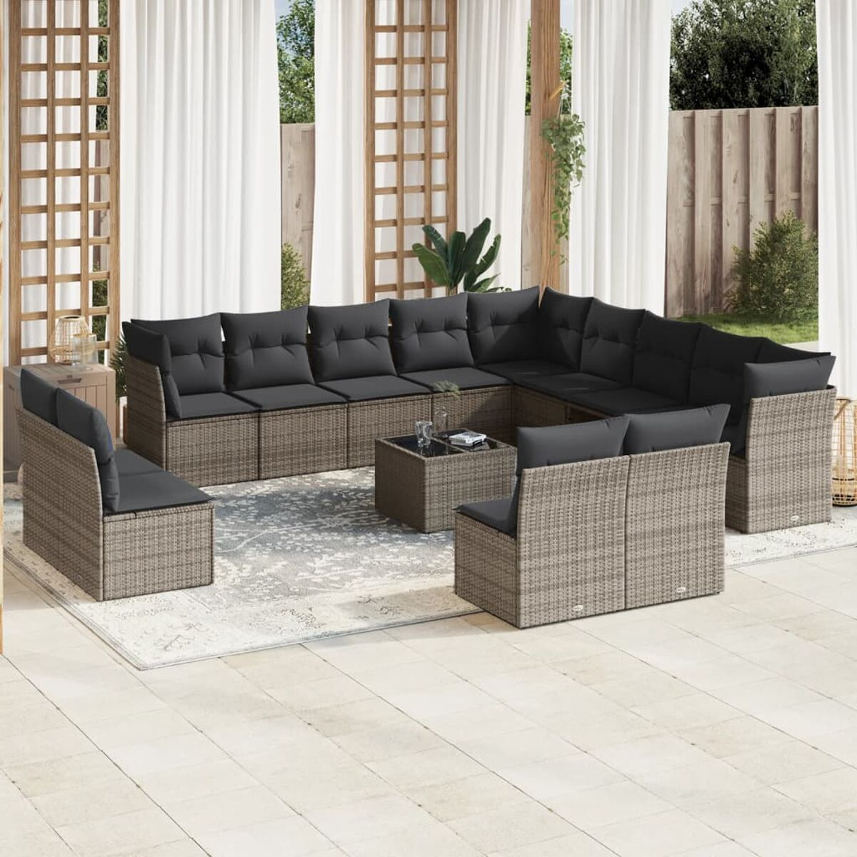 Ecksofa aus Korbgeflecht im Freien mit grauen Kissen. Es gibt einen quadratischen schwarzen Tisch.
