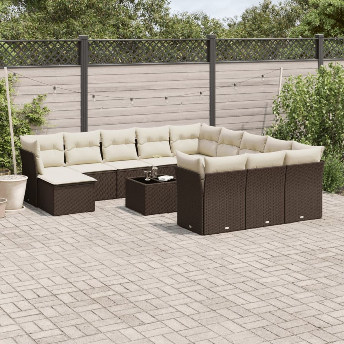 Set divano in rattan marrone con cuscini beige, tavolino e patio in mattoni.