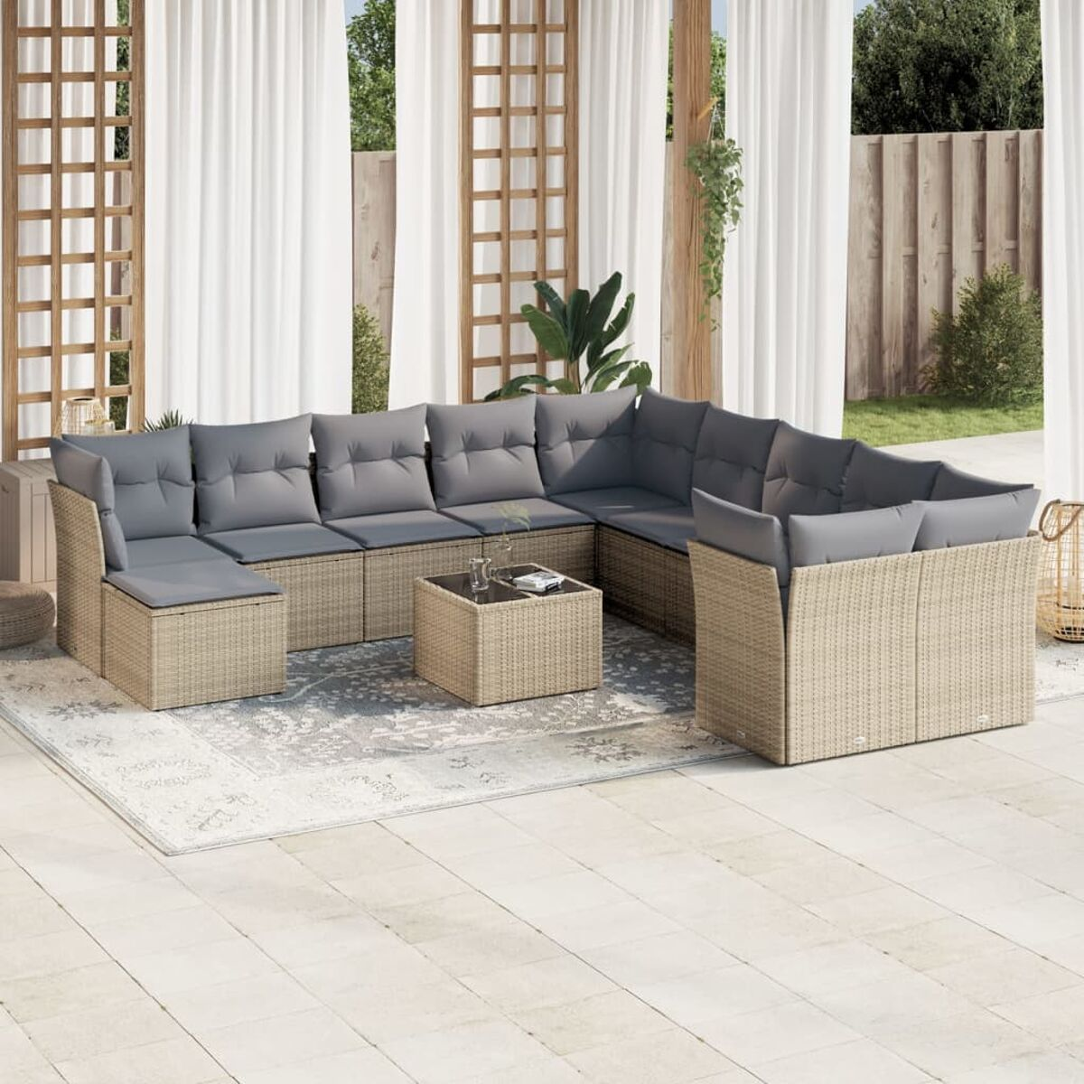 Beiges Korbgarnitur-Sofa mit grauen Kissen und einem quadratischen Couchtisch auf einer Terrasse mit Teppich.