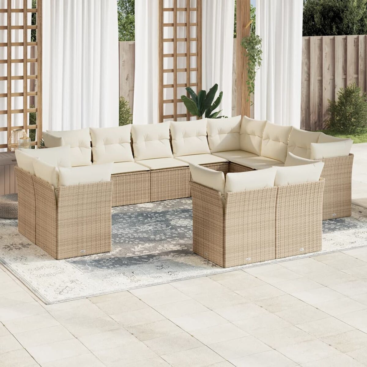 Gartensitzgruppe, helles Korbgeflecht mit cremefarbenen Kissen. Szene ist eine Terrasse mit Vorhängen und Teppich.