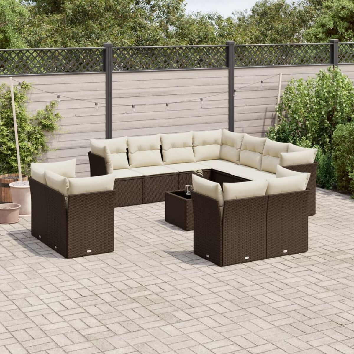 Set di mobili da patio con vimini marrone e cuscini color crema su un patio in mattoni.