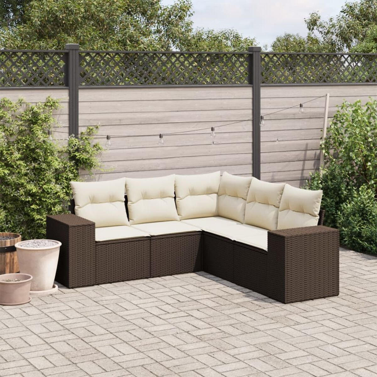 Divano componibile in rattan marrone con cuscini crema e tavolo quadrato sul patio.