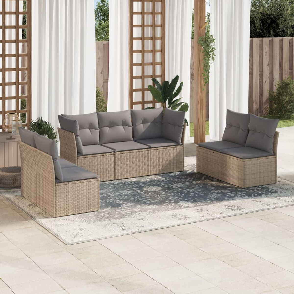 Beiges Outdoor-Sofaset aus Korbgeflecht auf einer Terrasse mit Teppich, Vorhängen und Pflanzen.