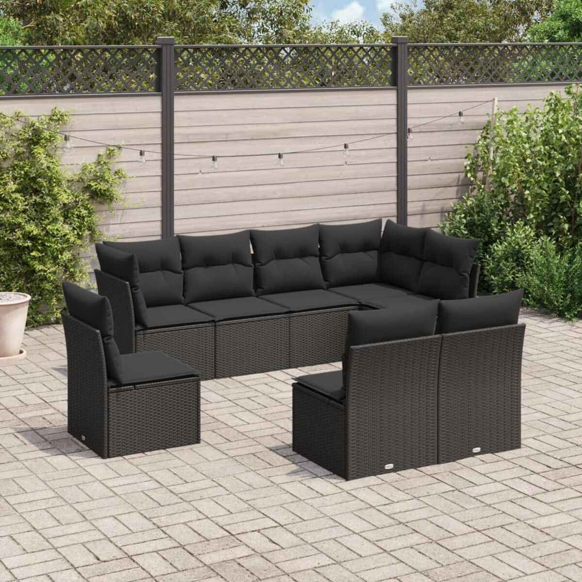 Schwarzes Outdoor-Möbelset aus Korbgeflecht. Enthält ein Ecksofa, zwei Sessel und einen Couchtisch. Backstein-Terrasse im Hintergrund.