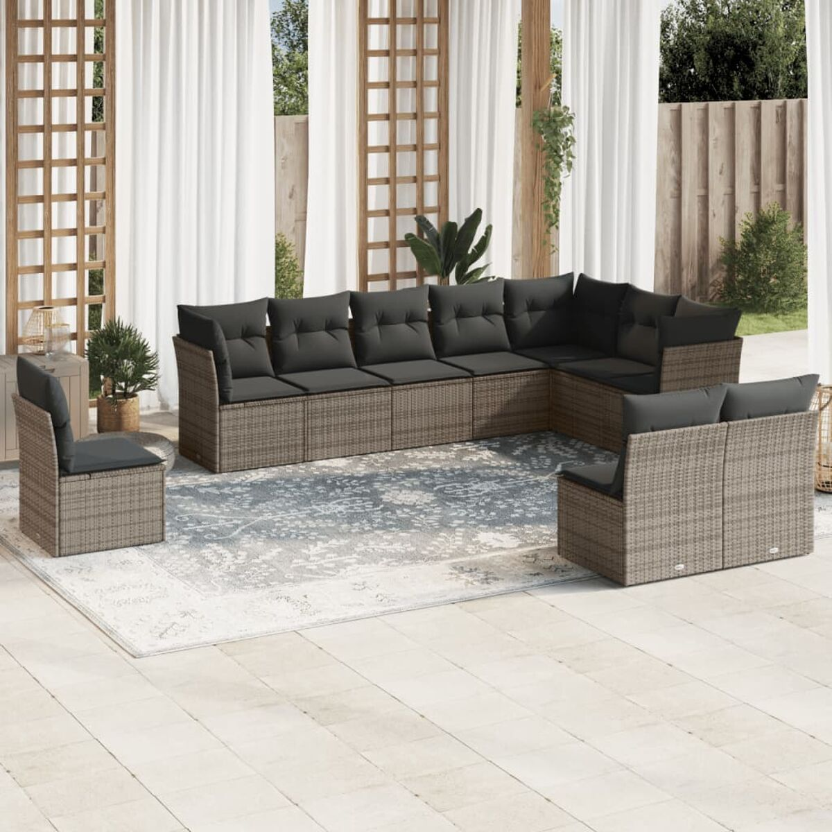 Outdoor-Wicker-Möbelset mit grauen Kissen auf einer Terrasse. Enthält Sofa, Stuhl und Tisch. Hintergrund: Vorhänge, Gitter.
