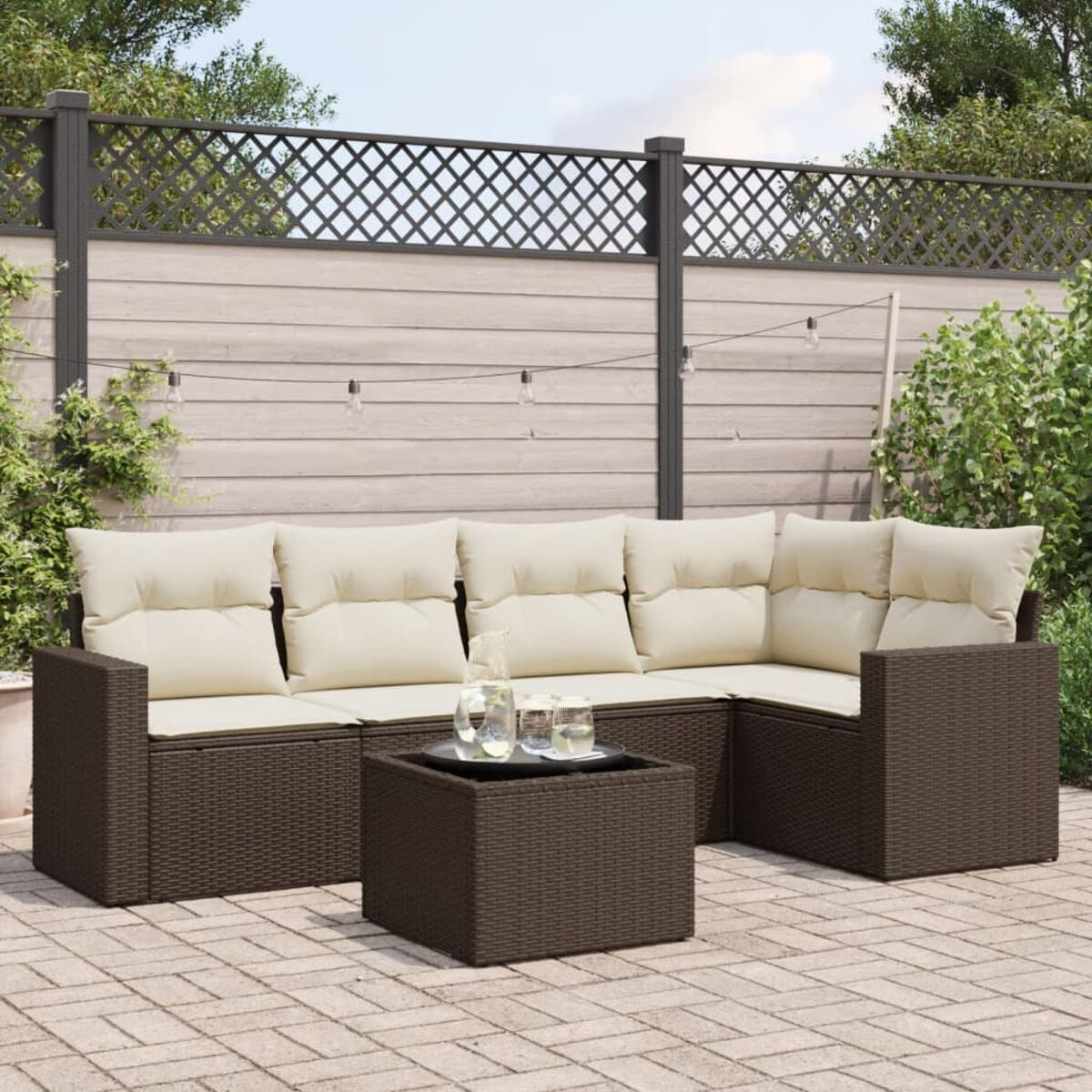 Divano in rattan marrone scuro con cuscini beige e tavolo quadrato.