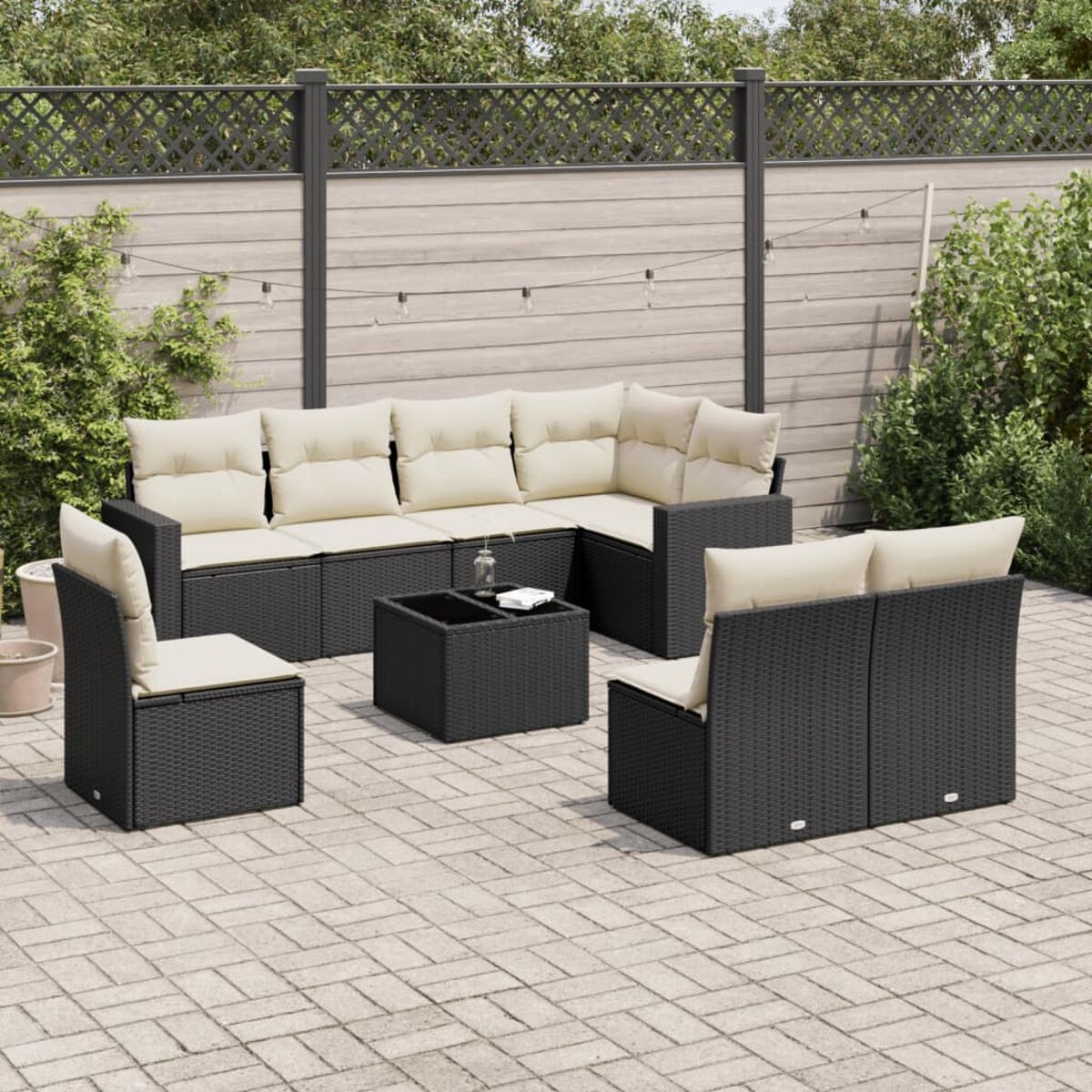Schwarzes Outdoor-Wicker-Möbelset mit beigen Kissen auf einer Terrasse.