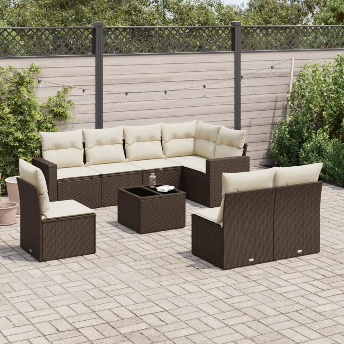 Set di mobili in rattan marrone per esterni: divano, due sedie e un tavolo. Superficie pavimentata.