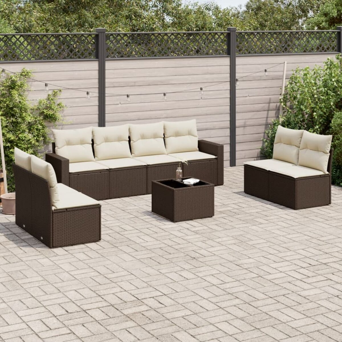 Set di mobili da esterno in vimini marrone su un patio in mattoni. Include divano, sedie e un tavolo con piano in vetro.