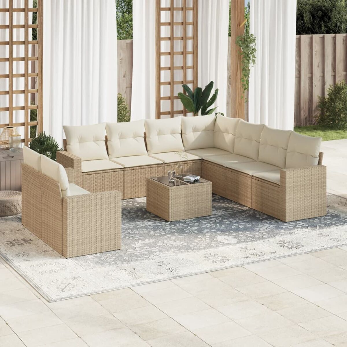 Outdoor-Ecksofa aus Korbgeflecht mit beigen Kissen und Couchtisch, auf einem Teppich, in der Nähe von Vorhängen.