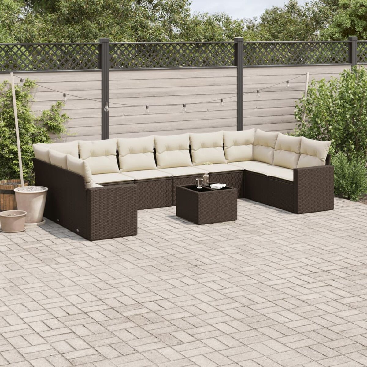 Braunes Korbmöbel-Set mit cremefarbenen Kissen, kleinem Tisch und Pflanzen auf der Terrasse.