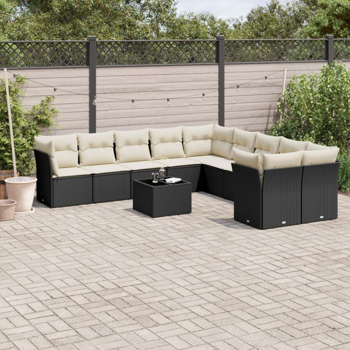 Schwarzes Rattansofa und Tisch mit beigen Kissen auf einer Terrasse.