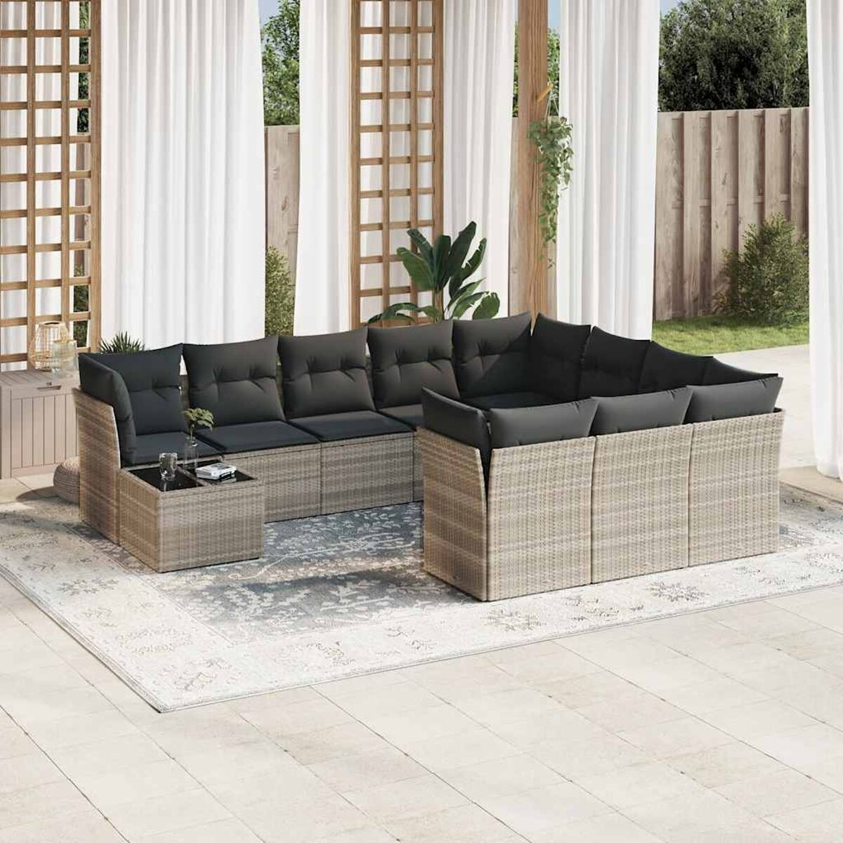 Terrassenset mit hellen Rattanmöbeln, grauen Kissen und sichtbaren Vorhängen.
