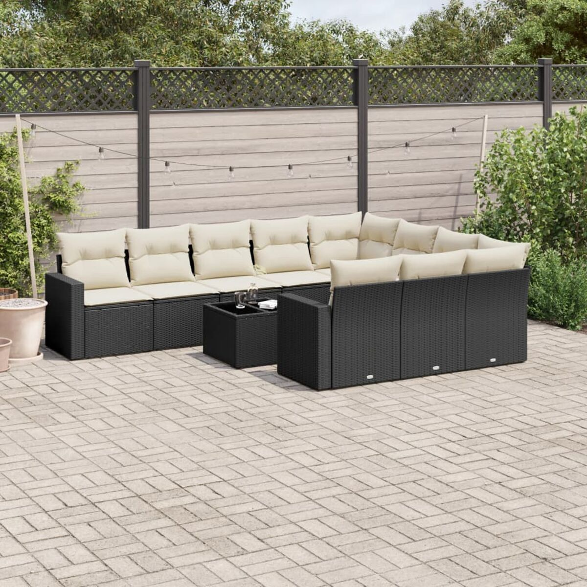 Schwarzes Rattansofa und Tisch mit beigen Kissen auf der Terrasse.