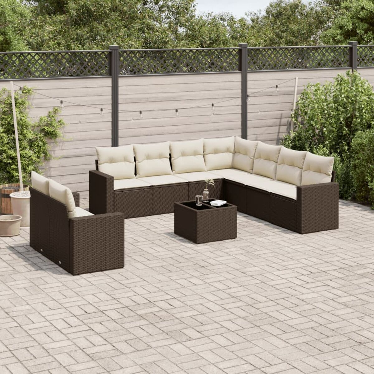 Divano componibile da esterno con cuscini color crema e tavolo. Include sedia, patio, recinzione e verde.
