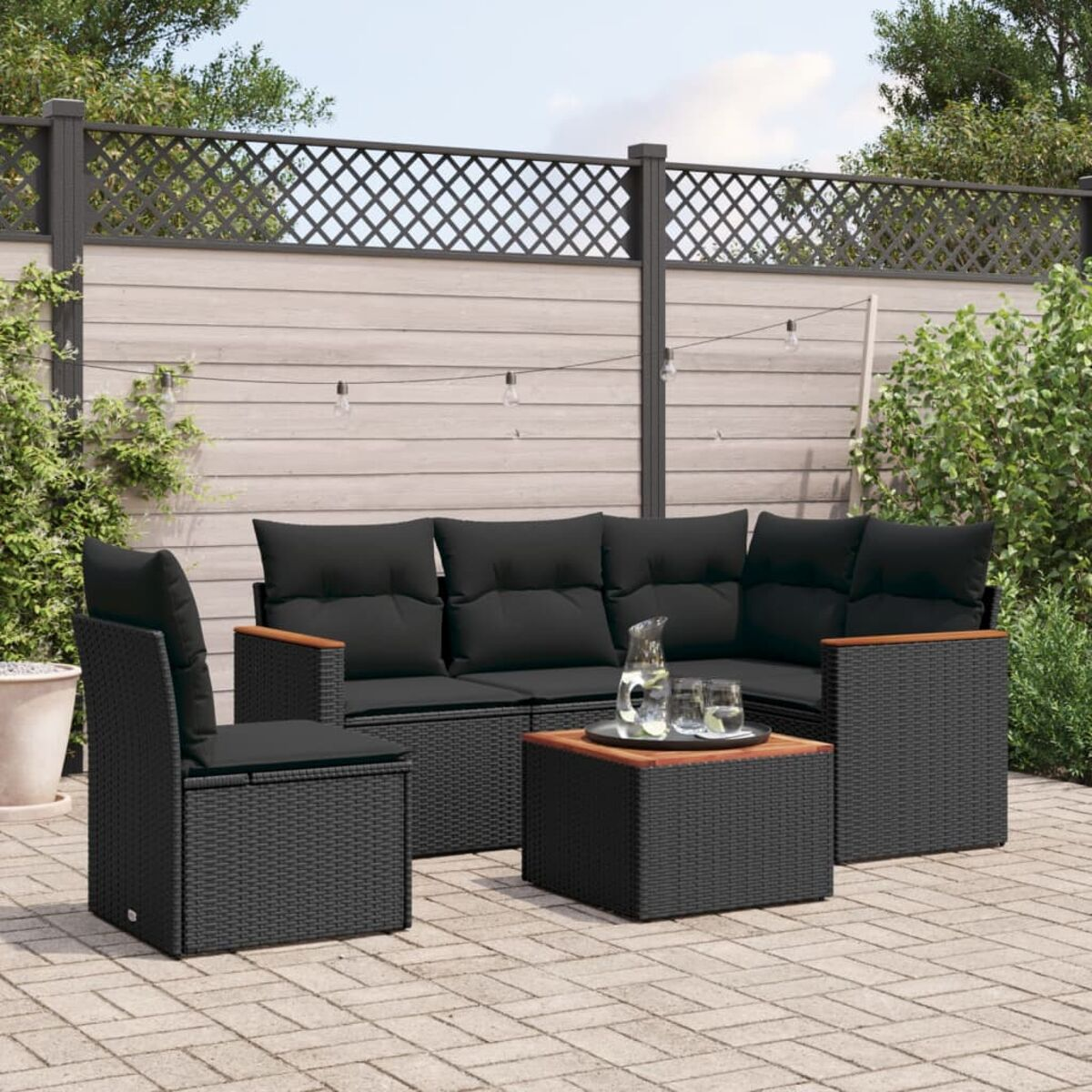 Schwarzes Korbmöbel-Set für die Terrasse. Enthält Sofa, Stuhl und Couchtisch auf Ziegeln.