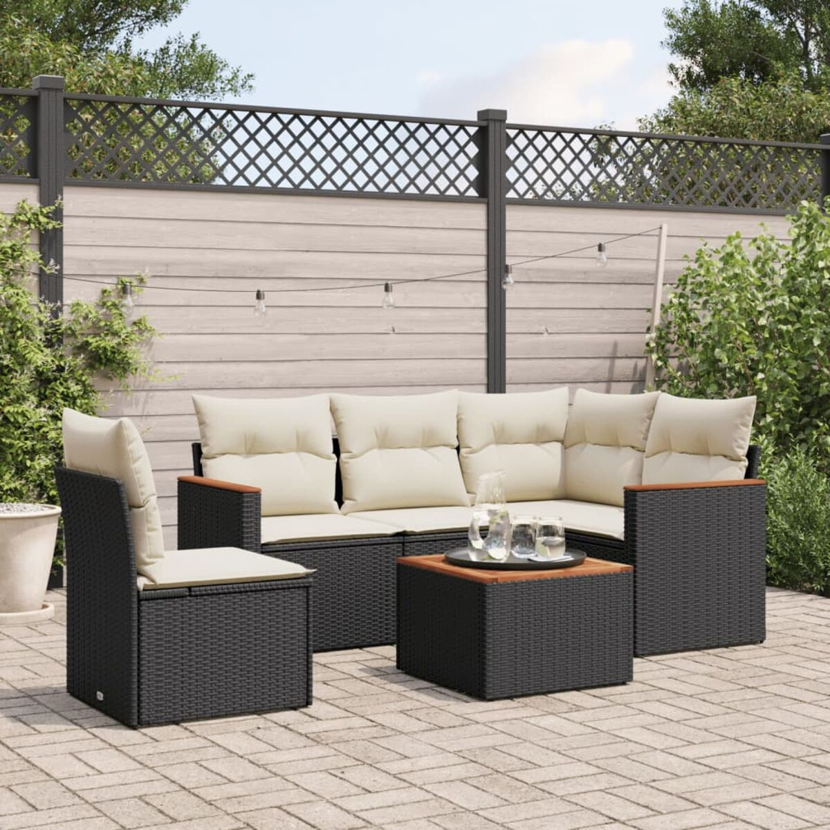 Schwarzes Outdoor-Set mit beigen Kissen. Enthält ein Sofa, einen Stuhl und einen kleinen Tisch.