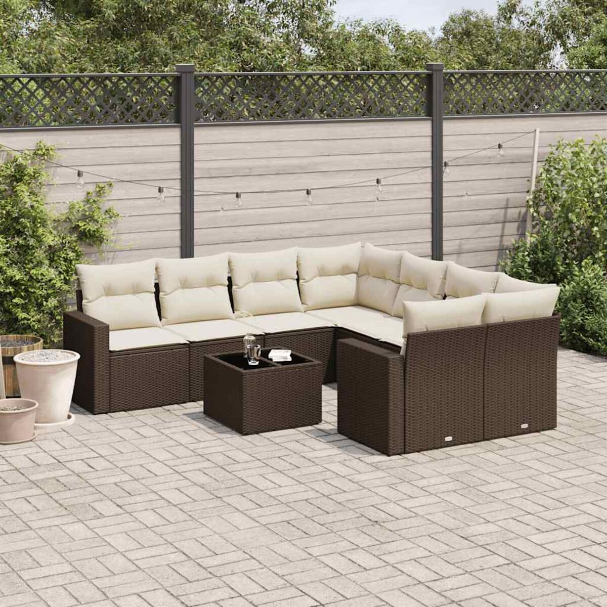 Set da patio esterno: divani in vimini marrone, cuscini beige e tavolino coordinato.
