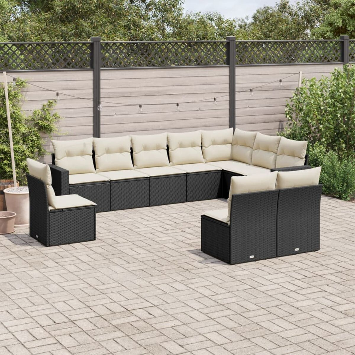 Schwarzes Ecksofa aus Korbgeflecht mit beigefarbenen Kissen auf Ziegelpflaster.
