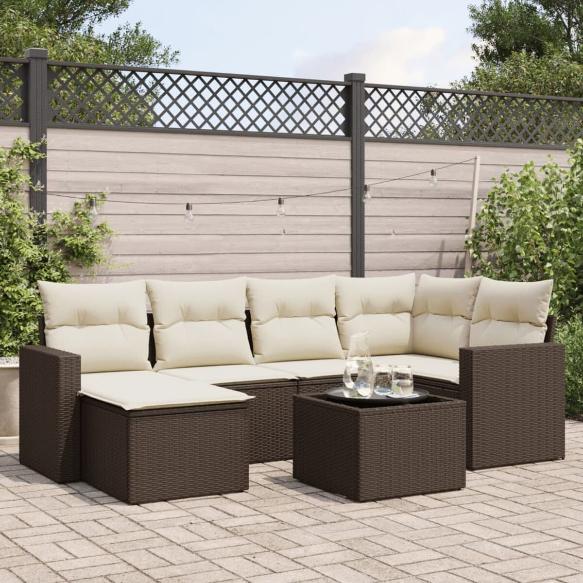 Seccional exterior de mimbre marrón con cojines beige, mesa de centro y patio de ladrillo.