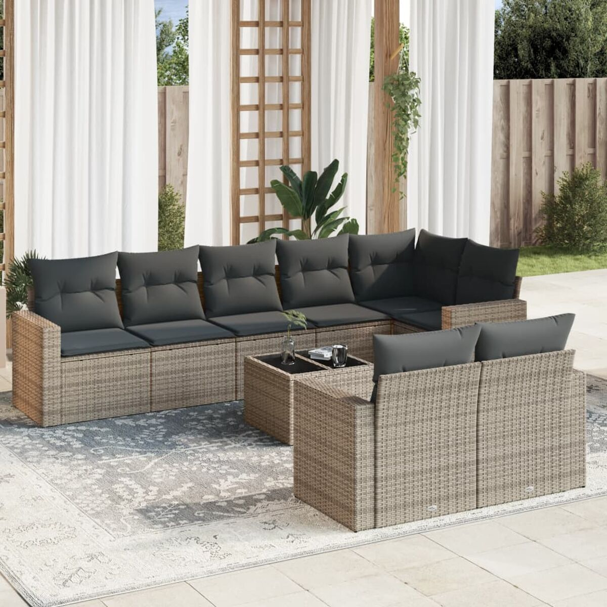 Ecksofa aus Korbgeflecht mit grauen Kissen, Couchtisch, Teppich und Sofa im Hintergrund.