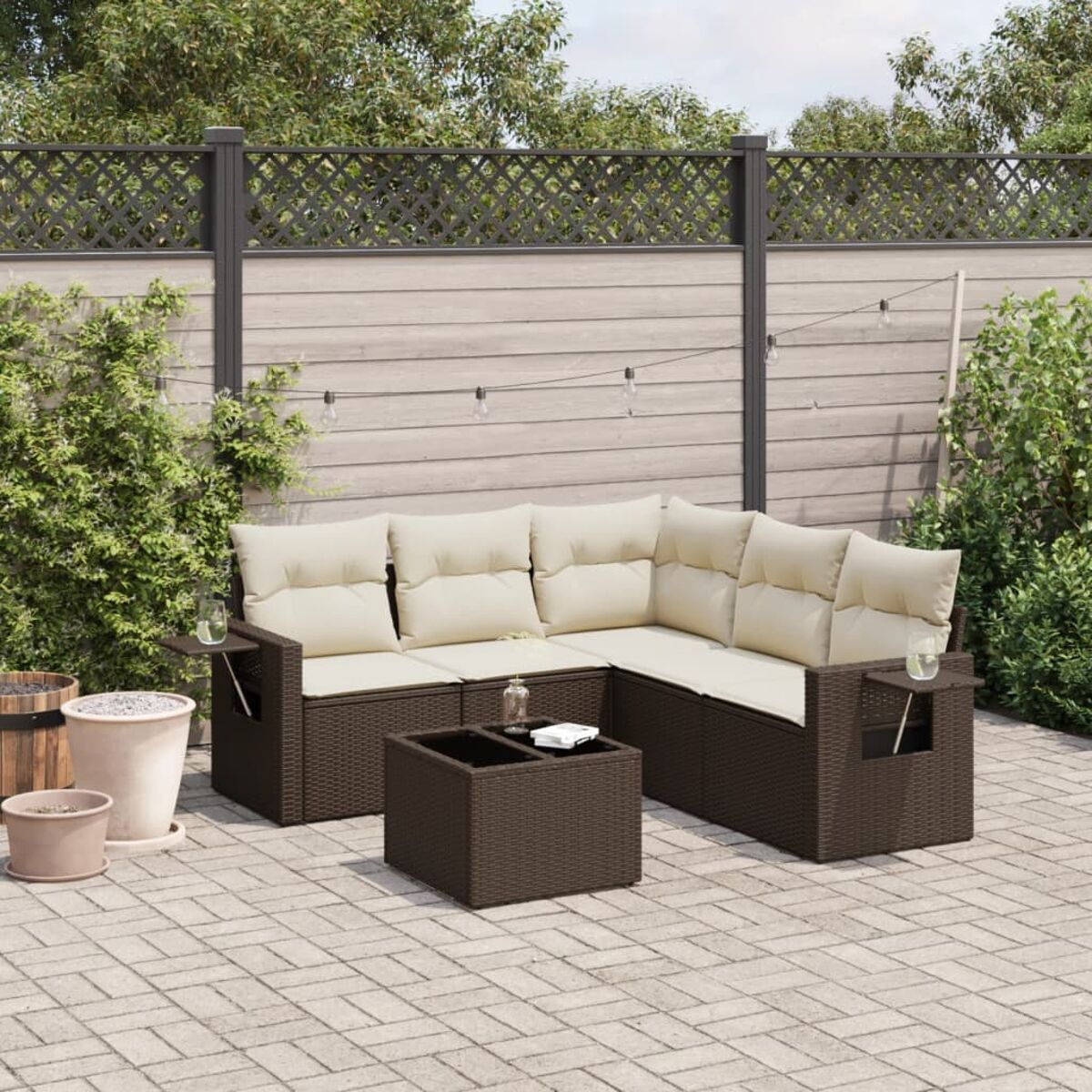 Set divani da esterno con vimini marrone e cuscini beige su un patio con tappeto.