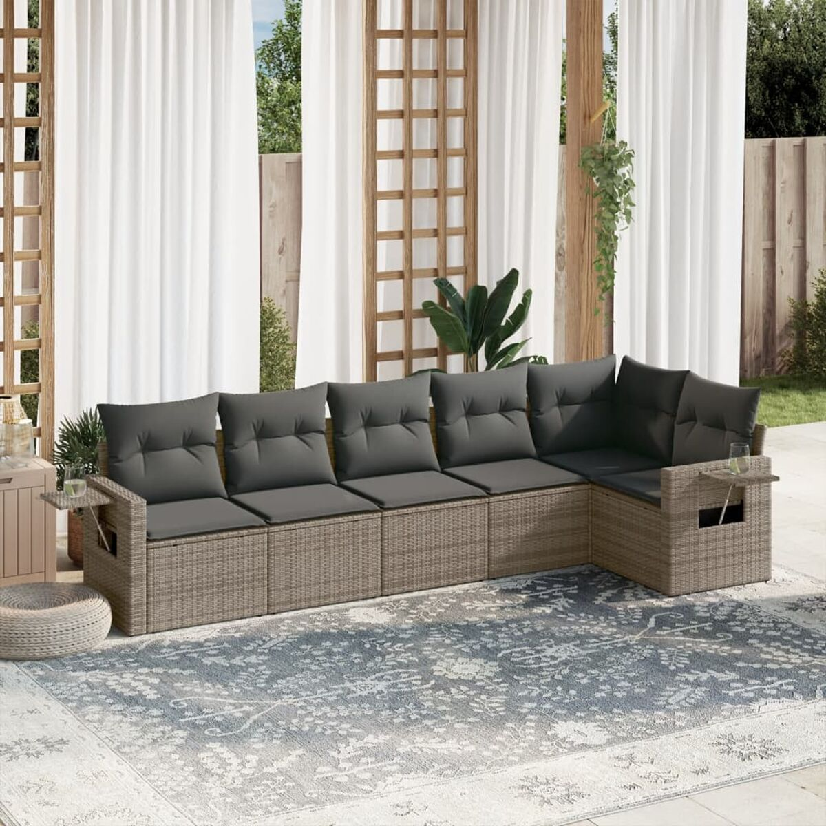 Beiges Outdoor-Sektionssofa aus Korbgeflecht mit grauen Kissen auf einer Terrasse.