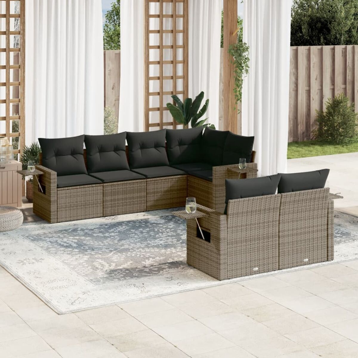 Graue Wicker-Sofagarnitur mit schwarzen Kissen und einem Couchtisch auf einer Terrasse.